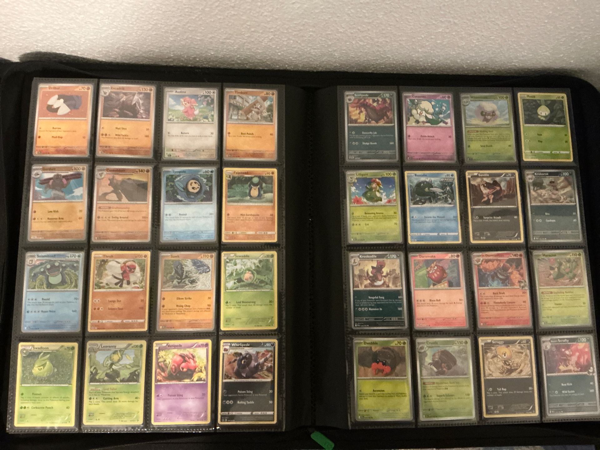 An open binder holding 32 sleeved Pokémon cards